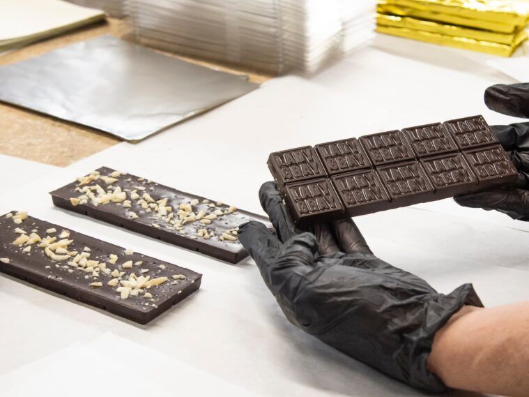 An employee inspects a freshly produced chocolate bar.